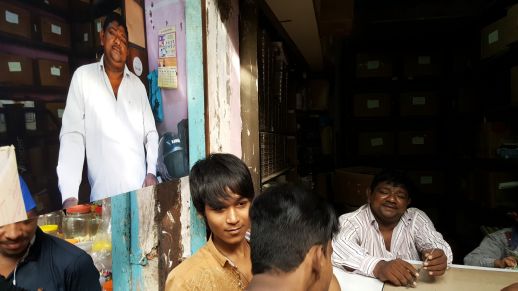 A shop owner posing by a photo of him exhibited in during the street exhibition we organized.