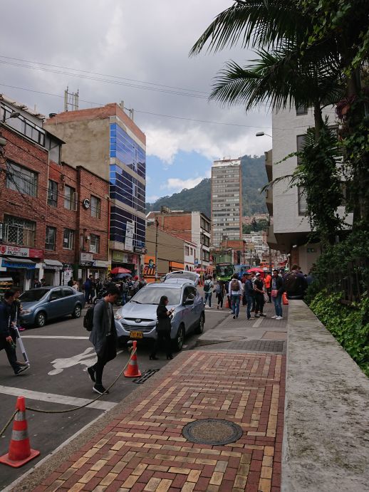 One of the University of Piloto buildings to the right with several shops on the left separated by a street