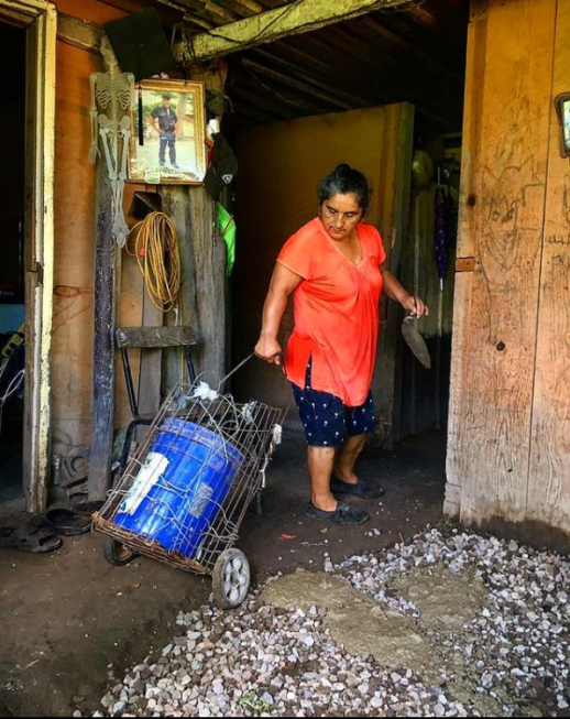 Tobias and Lucina mixing and pouring gravel and cement to temporarily repair damage caused by floods to the patio of Lucina’s home